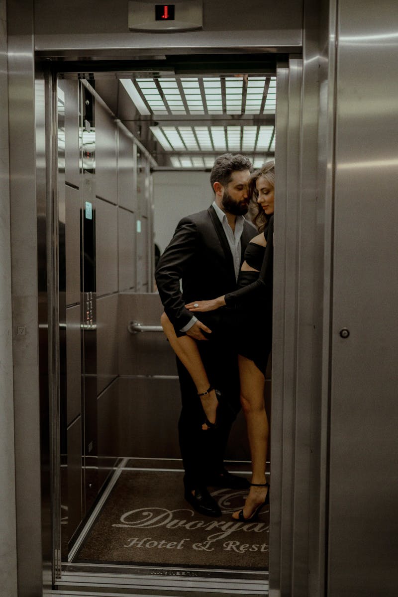 Chic couple sharing a tender moment inside a hotel elevator.